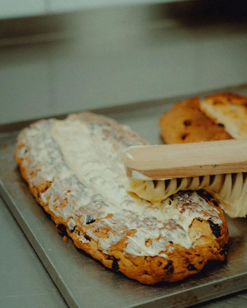 Gebackener Stollen wird mit dem Pinsel gebuttert