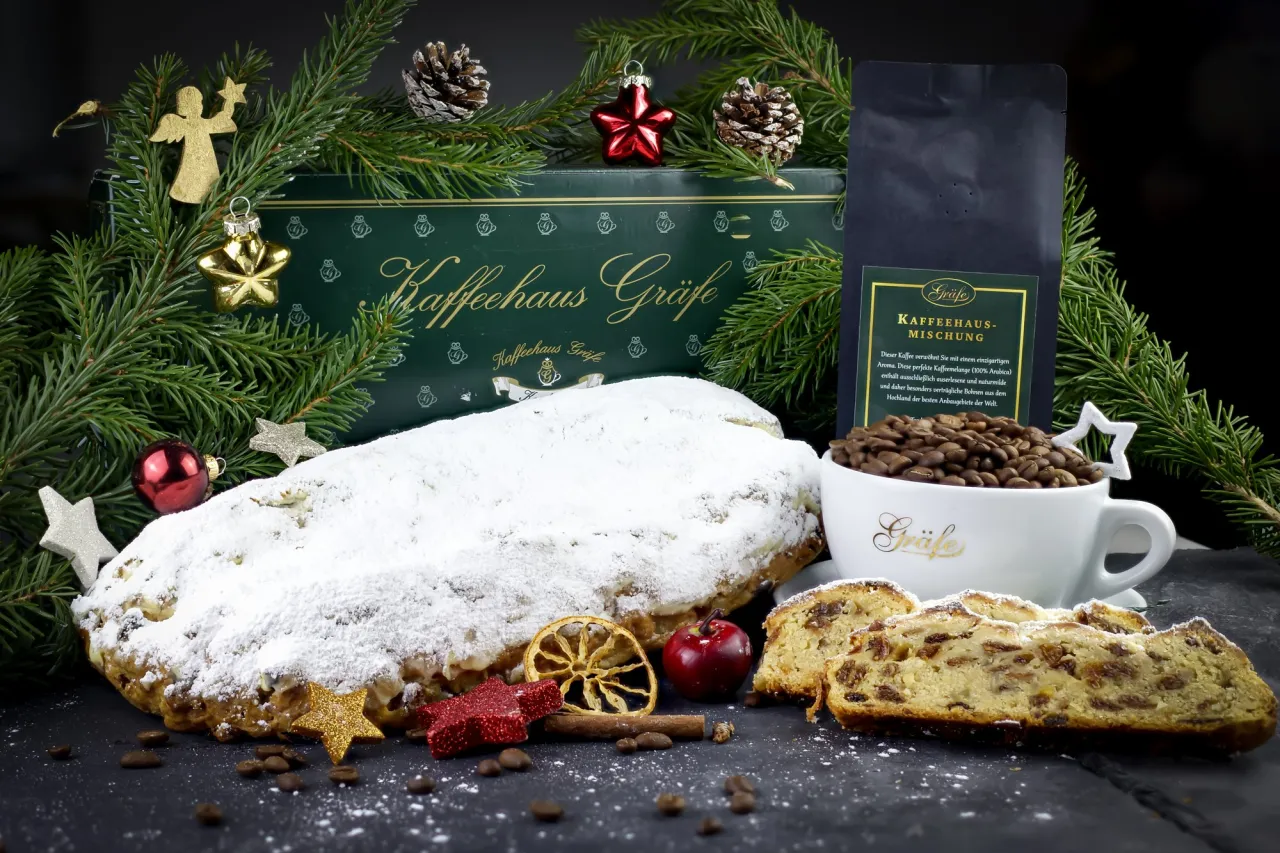 Gräfe Rosinenstollen, angeschnitten, mit Kaffee und Weihnachtsdeko vor den grünen Gräfe-Geschenkkartons