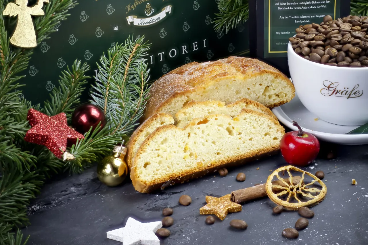 Angeschnittener Gräfe Quarkstollen mit einer Tasse Kaffeebohnen und Weihnachtsdeko